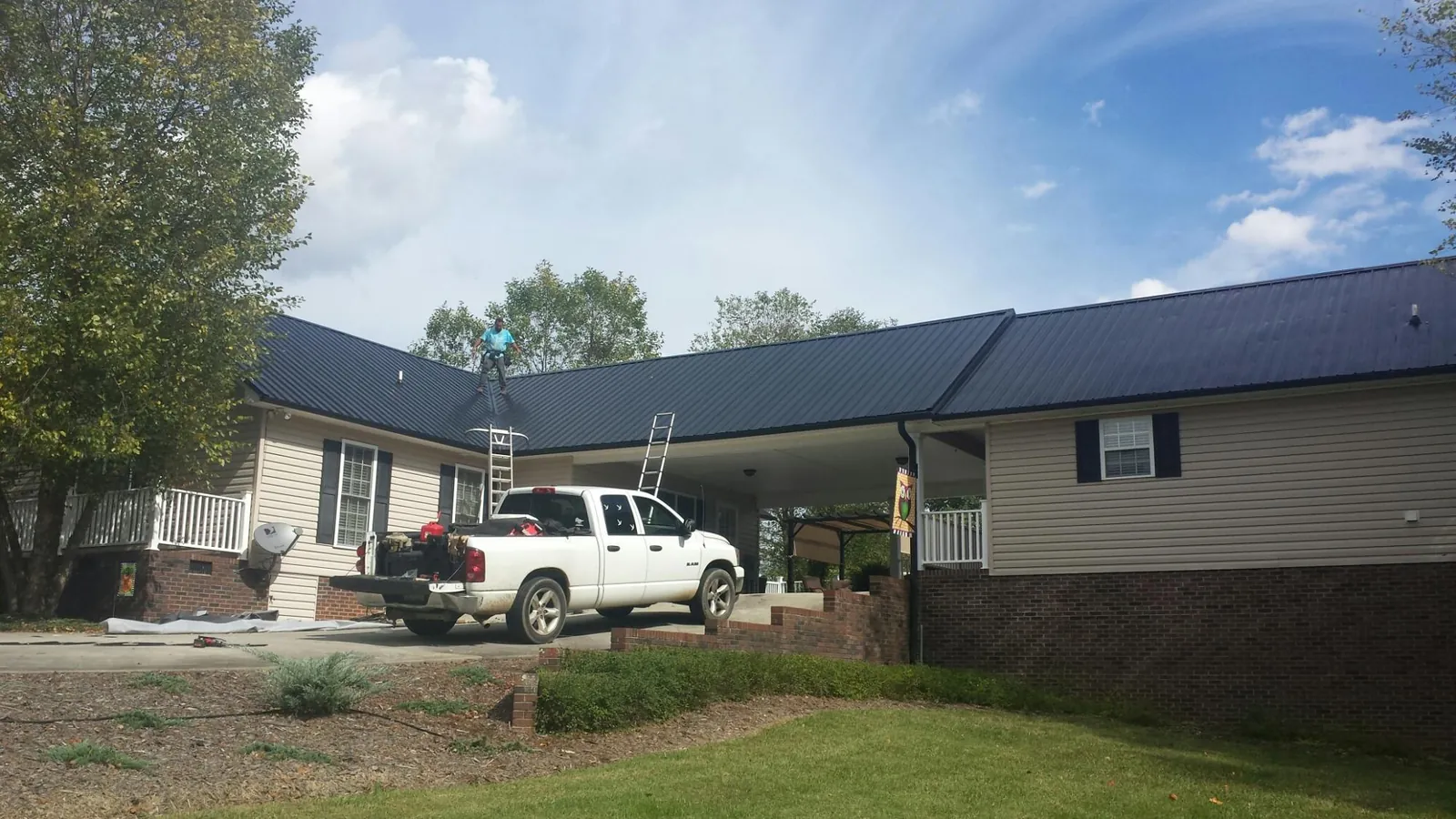 Black metal roof over a home and attached breezeway with ladders set in Saint Marys